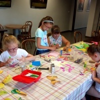 Dzieci wykonujące prace prace plastyczne przy stole.