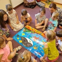 Dzieci siedzące na dywanie, które złożyły duże puzzle.