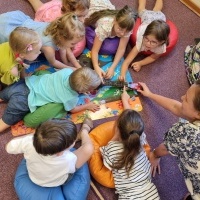 Dzieci leżące na dywanie i układające puzzle.