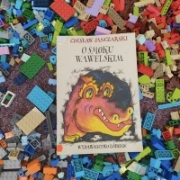 Rozsypane klocki lego na dywanie, na których jest położona książka.