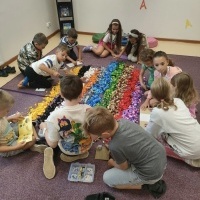 Grupa dzieci siedząca na dywanie i bawiąca się klockami LEGO.