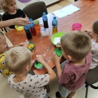 Dzieci stojące wokół stołu i robiące eksperymenty.